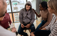 Diverse group of people sitting in circle in group therapy session