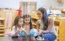 Teacher and two young students working with two globes