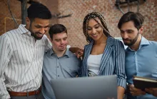 Cheerful young businesspeople with laptop working in office, social inclusion and cooperation