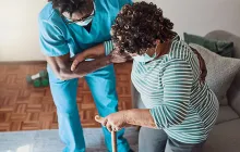 Shot of a young male nurse helping an elderly patient stand