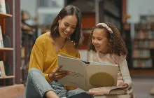 Mother and daughter reading together in library