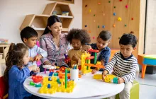 Preschool teacher playing blocks with young students