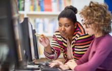 Two teachers looking at a computer monitor together.