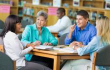 Four teachers meeting in a library 