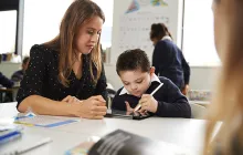 female teacher working with young student on tablet