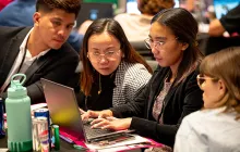 participants in Season of CS event looking at laptop together