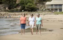 Three older women walking on a beach