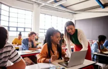 Teacher helping student at desk