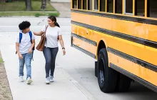 Mom walking preteen to schoolbus