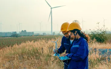 Workers in a field with wind turbines